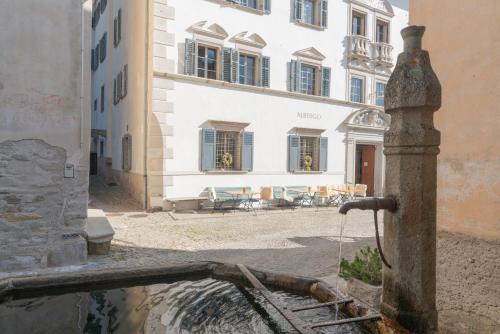 a water fountain in a street with a building at Hotel Palazzo Salis in Soglio