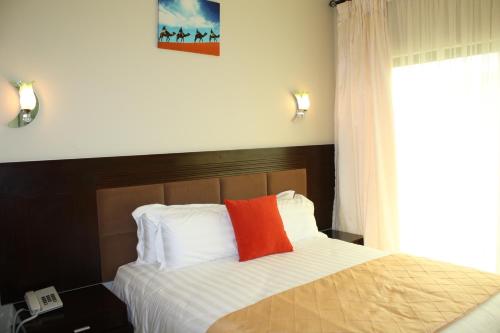 um quarto com uma cama com uma almofada vermelha em Nomads Court Chudleigh em Lusaka