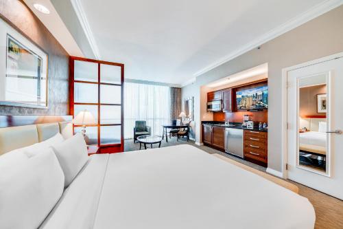 a bedroom with a large white bed and a kitchen at Jet Luxury Elite at The Signature in Las Vegas
