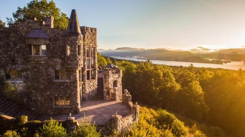 an old castle on a hill with a lake in the background at HIGHLANDS CASTLE overlooking Lake George plus 2 other CASTLES & SUITES in Bolton Landing
