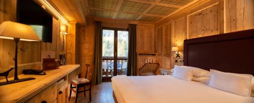 a bedroom with a bed and a table with a lamp at Gran Baita Hotel & Wellness in Courmayeur