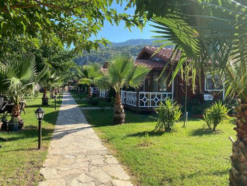 a path leading to a house with palm trees at Villa Efsane Hotel in Cıralı