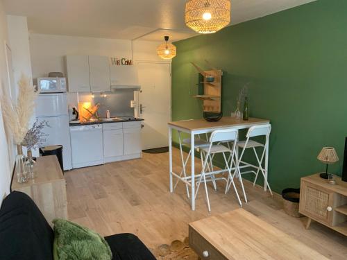 cocina y sala de estar con mesa y nevera en L'escale, en Courseulles-sur-Mer