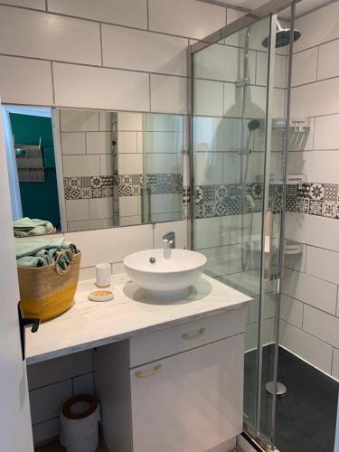 La salle de bains est pourvue d'un lavabo et d'une douche en verre. dans l'établissement L'escale, à Courseulles-sur-Mer