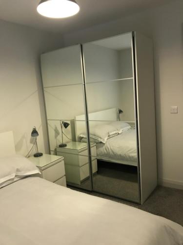 een spiegel in een slaapkamer met een bed en een lamp bij Fabulous Portstewart Modern Seaside House NITB in Portstewart