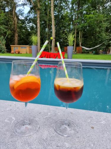 two wine glasses sitting on a table next to a swimming pool at Table et chambre particulière in Mons