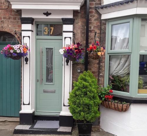 una casa con una puerta verde y cestas de flores en The Holly & Ivy, en Bridlington