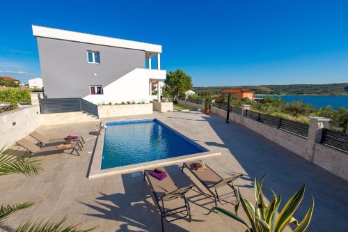 a swimming pool with chairs and a house at Vila Sole in Rtina