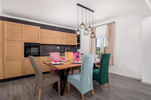 a kitchen with a wooden table and green chairs at Vila Sole in Rtina