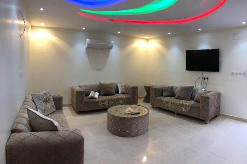 a living room with couches and a flat screen tv at فلل فندقية بمدينة تنومة in Ithnayn