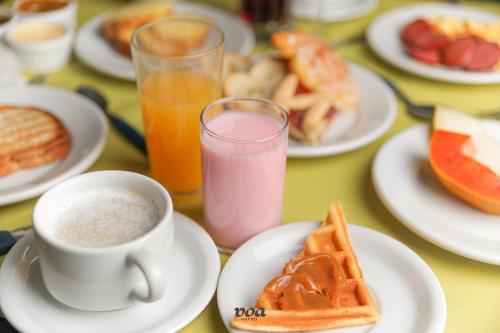 uma mesa com pratos de alimentos para o pequeno-almoço e uma chávena de café em VOA Villa Canoas em Foz do Iguaçu