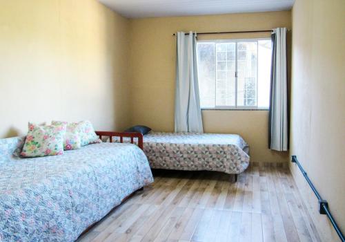 1 Schlafzimmer mit 2 Betten und einem Fenster in der Unterkunft Casa com churrasq e Wi-Fi na Praia de Itacuruca RJ in Mangaratiba