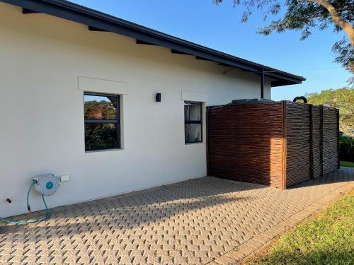 a white house with a wooden fence next to it at the mod pod studio in Mtunzini