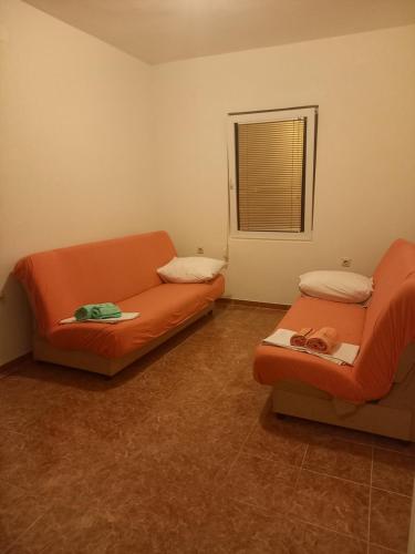 a living room with an orange couch and a window at Apartmani Stojanović in Sutomore
