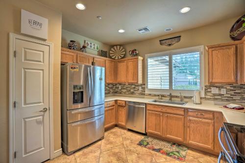 a kitchen with wooden cabinets and a stainless steel refrigerator at Luxe Anthem Home with Grilling Patio Near Hiking! in Anthem