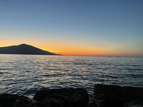 a sunset over a large body of water with rocks at Eriola apartament in Orikum