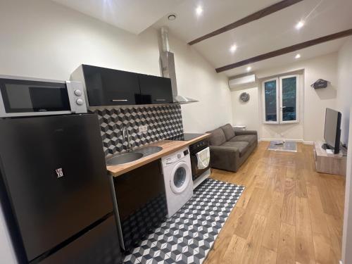 eine Küche mit einem schwarzen Kühlschrank und ein Wohnzimmer in der Unterkunft T2 centre ville au calme absolue in Marseille