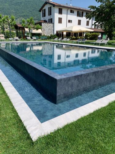 a large swimming pool with blue water in front of a house at Agriturismo Cà Del Lago in Gravedona