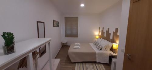 アルジェズールにあるCasa Bárbara - No centro histórico de Aljezurの白い部屋(ベッド1台、ランプ2つ付きのテーブル付)