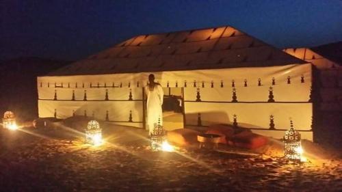 a man standing in front of a building at night at Bivouac ZAGORA in Zagora