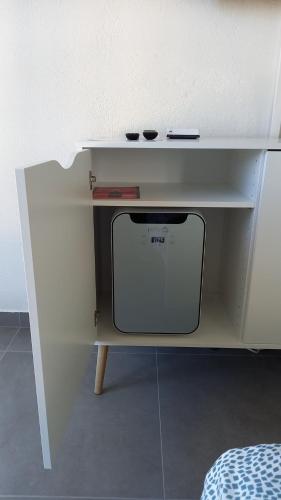 a white shelf with a microwave under a table at Aloha chambres in Port-Valais