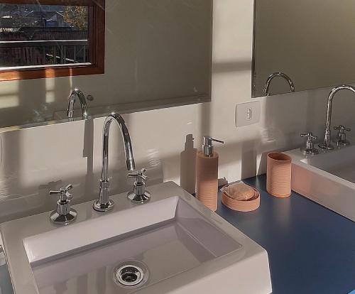 a bathroom with a white sink and two mirrors at Casa Três Rios - Campos do Jordão in Campos do Jordão
