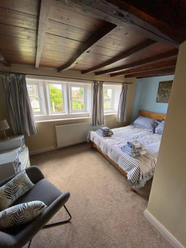 a bedroom with two beds and a chair in it at Lavender Cottage - 18th Century Characterful Space 