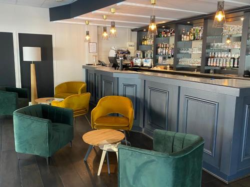 un bar avec des chaises jaunes et vertes et un comptoir dans l'établissement Hotel Restaurant Saint-Benoit, à Gueugnon