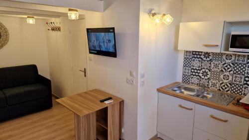 Il comprend une petite cuisine avec un canapé et une télévision murale. dans l'établissement Les Cabestans 3 proche Lydia, au Barcarès