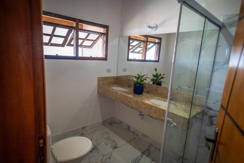 uma casa de banho com 2 lavatórios e uma cabina de duche em vidro. em Mar Egeu Arte & Pouso em Peruíbe