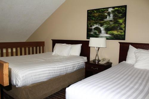 a hotel room with two beds and a lamp at Ramada by Wyndham Campbell River in Campbell River