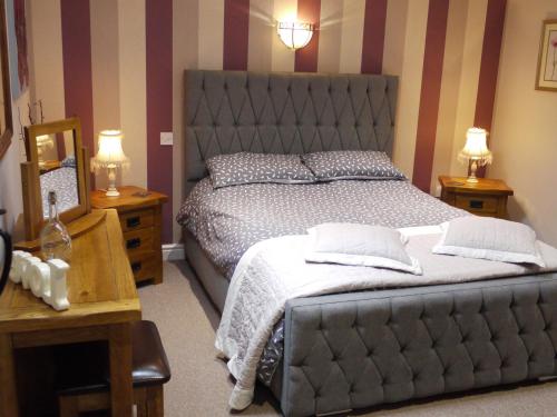 Cwm Derw Cottage في Llanafan-fawr: غرفة نوم بسرير كبير وموقف ليلتين