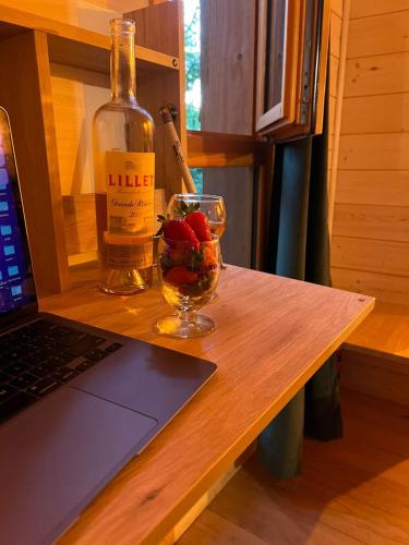 a bottle of wine and a glass of fruit on a table at Charmante Cabane dans les arbres avec jacuzzi et sauna in Boismorand