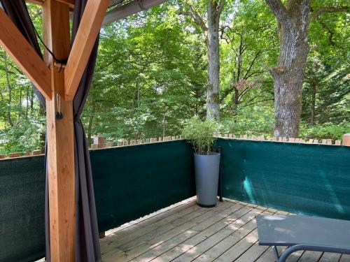 a screened porch with a green fence and a bench at Charmante Cabane dans les arbres avec jacuzzi et sauna in Boismorand