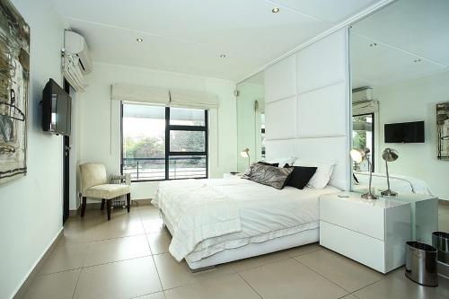 a white bedroom with a bed and a mirror at The Odyssey Lifestyle Complex Morningside - 2 BR in Johannesburg