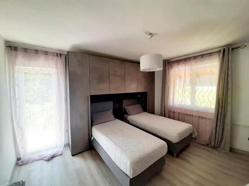 1 dormitorio con 2 camas y 2 ventanas en NAT Apartments, en Koper