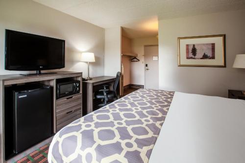 a hotel room with a bed and a flat screen tv at Baymont by Wyndham Northwood in Northwood