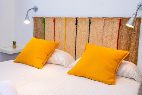 Una cama con dos almohadas amarillas encima. en Eslanzarote El Ancla House, wifi, Sea views, en Caleta de Sebo