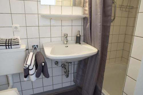 ein weißes Bad mit einem Waschbecken und einer Dusche in der Unterkunft Haus Frauenpreiss Whg. 61 in Cuxhaven
