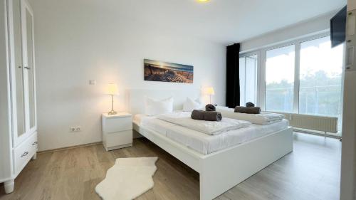 ein weißes Schlafzimmer mit einem großen Bett und einem großen Fenster in der Unterkunft Strandhaus Nordseebrandung Fewo A4.2 in Cuxhaven