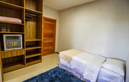 a small room with a bed and a tv at Pousada Suiça Mineira Centro in Monte Verde