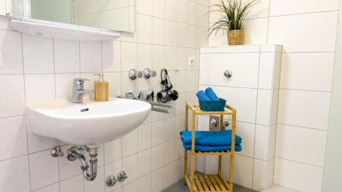 ein weißes Badezimmer mit einem Waschbecken und einem Spiegel in der Unterkunft Strandhaus Nordseebrandung Fewo C1.1 in Cuxhaven