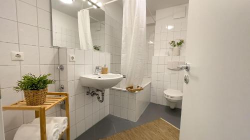 La salle de bains blanche est pourvue d'un lavabo et de toilettes. dans l'établissement Strandhaus-Nordseebrandung-Fewo-A4-3, à Cuxhaven