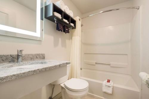 a bathroom with a toilet and a sink and a tub at SureStay Hotel by Best Western Thomson in Thomson