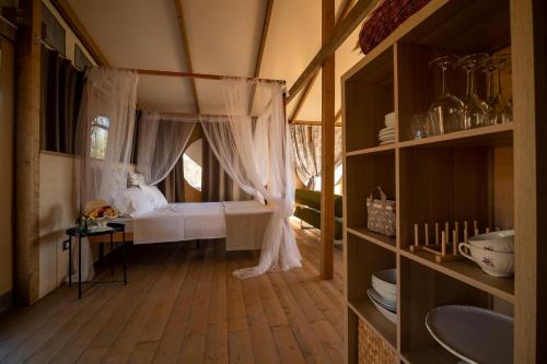 1 dormitorio con 1 cama con cortinas y suelo de madera en Glamping Podere San Jacopo, en Massa Marittima