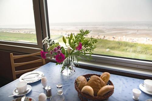 a table with a basket of bread and a vase of flowers at Haus-Seehund-16 in Cuxhaven