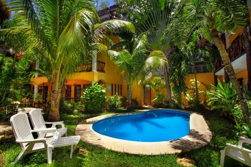 una piscina frente a un edificio con palmeras en Hotel Bosque Caribe, 5th Av. zone, en Playa del Carmen