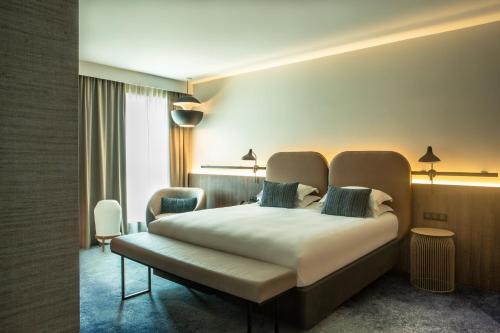 a hotel room with a bed and a chair at Crowne Plaza - Nice - Grand Arenas by IHG in Nice