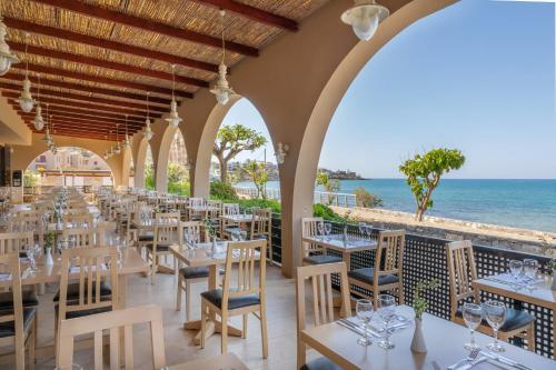 a restaurant with tables and chairs with the ocean in the background at Blue Sea Beach Affiliated By Melia in Stalida