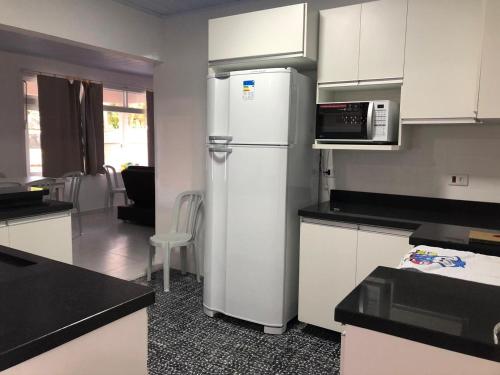 een keuken met een koelkast en een magnetron bij CASA DE PRAIA - Centro - Guaratuba in Guaratuba